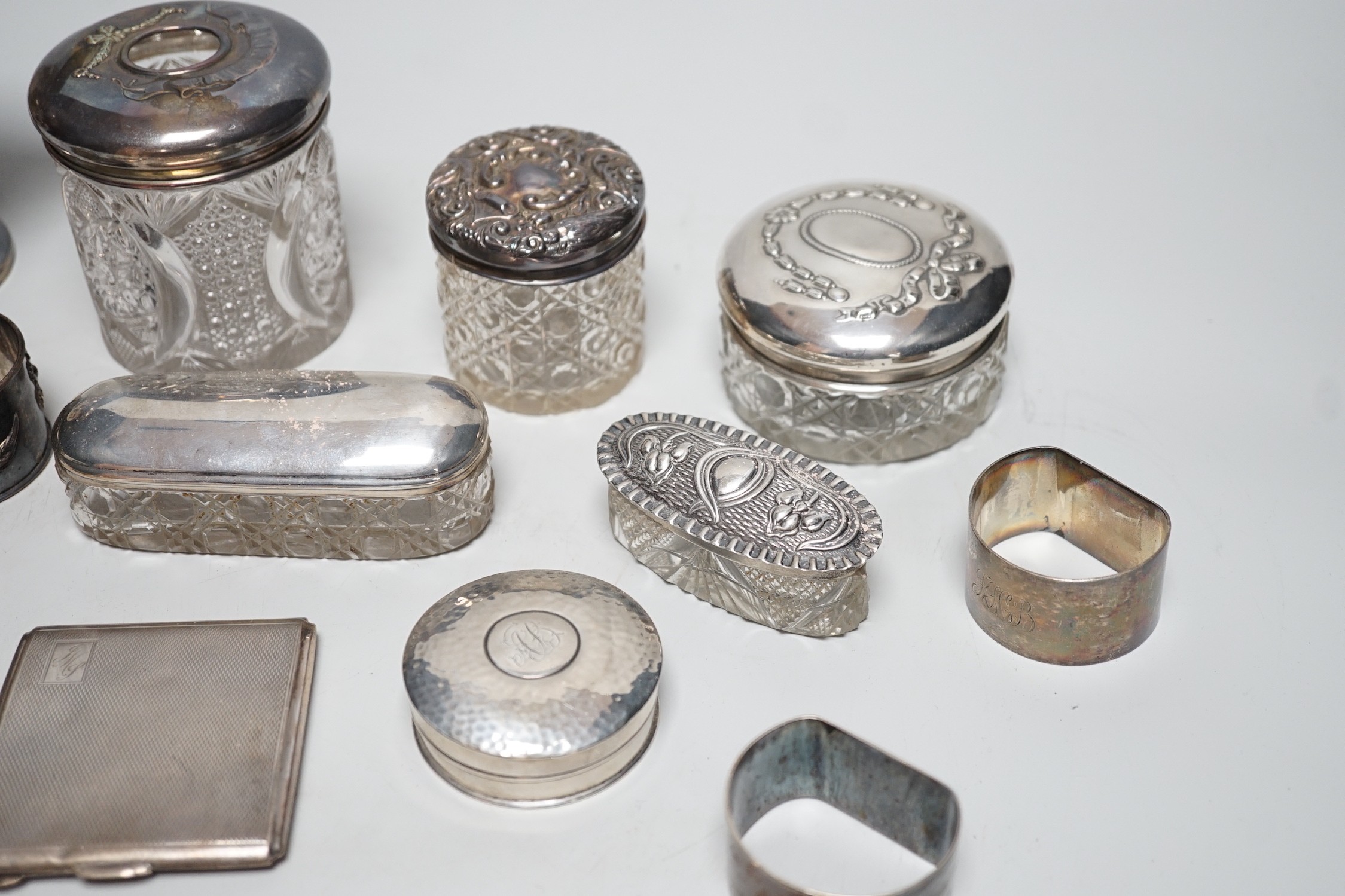 Sundry silver items, including a 1930's silver presentation cup, height 10.9cm, five silver or white metal mounted glass toilet jars, two silver napkin rings, two compacts, silver flatware and two Chinese white metal nap